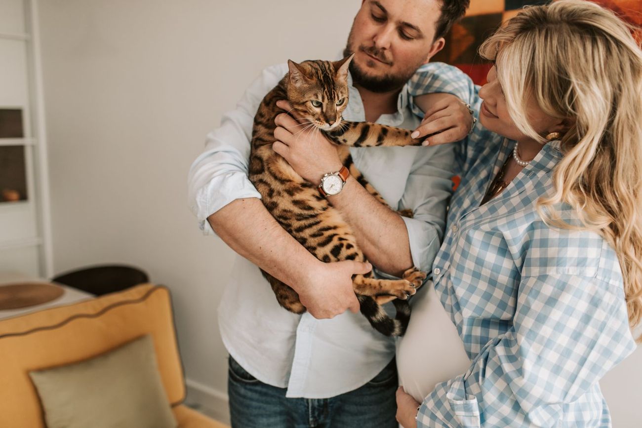 Casal acolhendo seu gato em casa, em um momento de vínculo da família multiespécie
