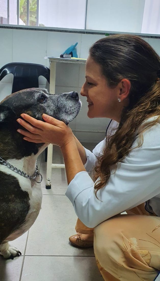 Dra. Maria Angélica sorrindo de rosto colado com um cão idoso